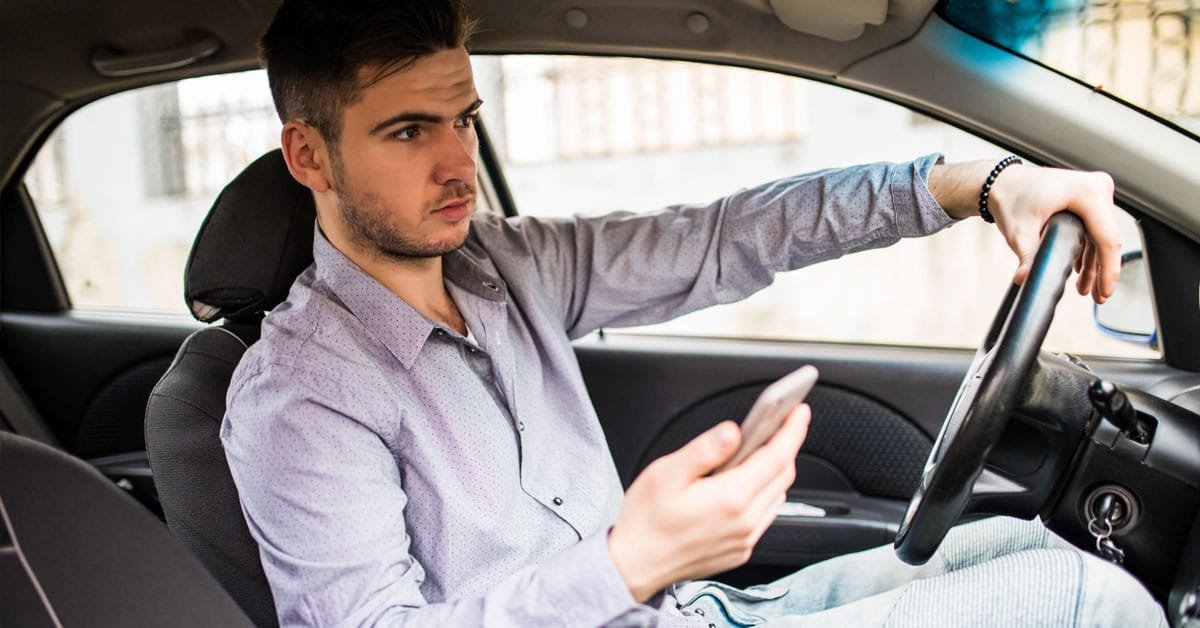 Empréstimo online com garantia: É possível contratar sem sair de casa? 1 Pessoa contratando empréstimo online com garantia pelo celular, sem sair do carro